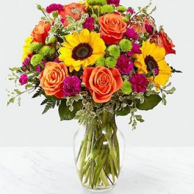 The Color Craze Bouquet blooms with a vibrant energy to create a special moment for your recipient! Our floral professionals weave together a blend of orange roses, sunflowers, violet mini carnations, green button poms, and lush greens to create an incredible gift. Presented in a clear glass vase, this truly colorful display of fresh flowers is ready to send your warmest birthday, thank you, or get well wishes straight to their door.

STANDARD bouquet is approx. 15H x 12W.
DELUXE bouquet is approx. 15H x 13W.
PREMIUM bouquet is approx. 16H x 14W.