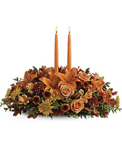 Graciously gather your family around the warm glow and classic autumn colors of this stunning Thanksgiving centerpiece. A lush variety of burnt orange blooms are gathered under a pair of tall, graceful candles - perfect for decorating your Thanksgiving dinner table, entryway or hearth.
Fall flowers include orange roses, orange asiatic lilies, dark orange alstroemeria, bronze button mums, yellow cushion mums, rust cushion mums, green oregonia and green huckleberry.
Accented with oak leaves and two orange taper candles.