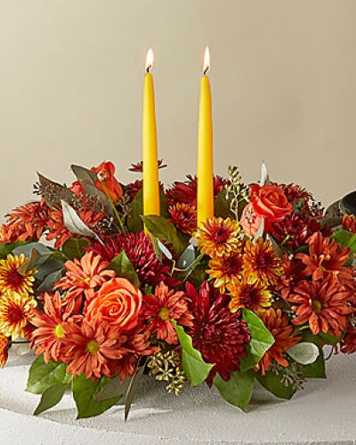 <p>Cast your holiday meals in a whole new light with this lovely centerpiece, which draws from the season’s most stunning bronze, red and orange florals and foliage.</p>